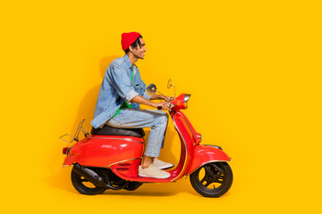 Full body photo of attractive young man driving ride retro red moped dressed stylish jeans clothes isolated on yellow color background - obrazy, fototapety, plakaty
