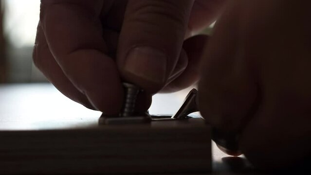 Installing hinges on a furniture door using an electric screwdriver. A man is assembling furniture.