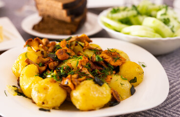 Baked potatoes with chanterelles, served with herbs on white plate