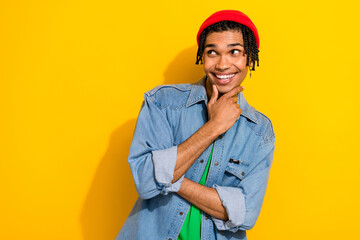 Photo of minded nice man stylish jeans clothes piercing earrings arm touch face look offer empty space isolated on yellow color background