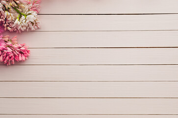 Pink and white flowers, on a light wooden background, space for text. 