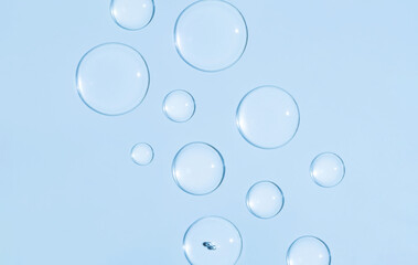 round drops of transparent gel serum on blue background