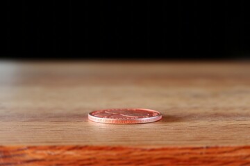 One small denomination coin on a wooden table. - obrazy, fototapety, plakaty