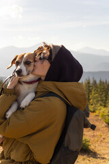 a young woman with a beagle dog stands on the background of a mountain range