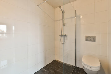 a modern bathroom with white walls and black tiles on the floor, there is a toilet in the corner next to the shower