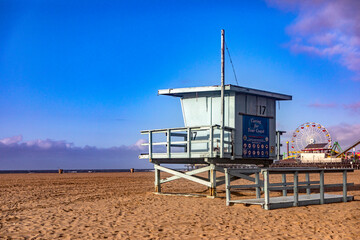 Beautiful photograph of a lifeguard hut with the Santa Monica Pier amusement park in the background and over the Pacific Ocean, on the west coast of California in the United States of America.