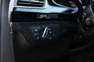 Fog lights switch in luxury automobile. Interior detail of modern car headlights controls being activated in low visibility conditions