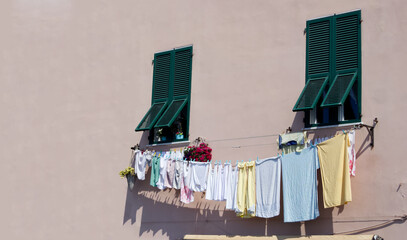 Washed clothes drying on a clothesline outside windows with green wooden shutters copy space