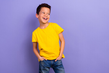 Photo of glad joyful boy wear yellow stylish clothes hands in pockets look special news empty space isolated on purple color background