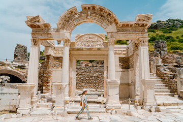 Tourist (woman) in the ancient city of Ephesus in Turkey with historic ruins in the background.