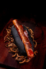Typical Halloween hot dog with witch's finger on black bread with ketchup blood served on wooden...
