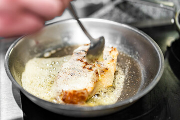 Professional chef cooking beef steak in frying pan on stove in restaurant kitchen