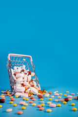 Buy and shopping medicine concept. Various capsules, tablets and medicine in the shopping cartt on a blue background