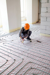Woman worker is installing underfloor heating system. Warm floor heating system