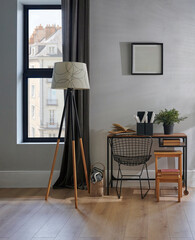 Decorative room chair, table, laptop, vase of plant, lamp and frame in front of the grey wall,...