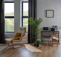 Decorative room chair, table, laptop, vase of plant, lamp and frame in front of the grey wall, brown curtain, parquet interior design, working corner.