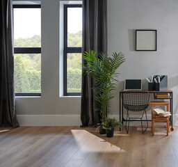 Decorative room chair, table, laptop, vase of plant, lamp and frame in front of the grey wall, brown curtain, parquet interior design, working corner.