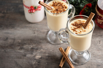 Homemade eggnog with cinnamon on wooden table. Typical Christmas dessert. Copy space