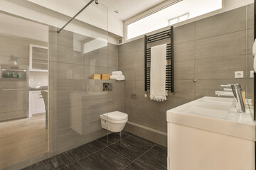a modern bathroom with gray tile walls and black tiles on the floor, along with a white toilet in the corner