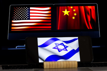 American and Chinese flags on screen of computer, Isreal flag displayed in front on smartphone...