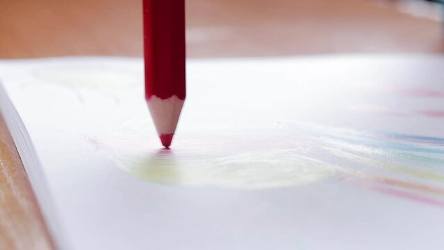 A child draws with a colored pencil in an album. Children's creativity, learning in kindergarten, school or at home. Pencil close up, selective focus. Color the picture