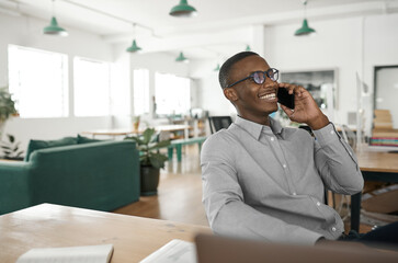 Smiling young African businessman talking on his phone at work