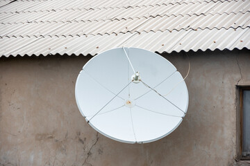 Satellite TV antenna on the wall of the house. Round white antenna receiver for radio signal. City...