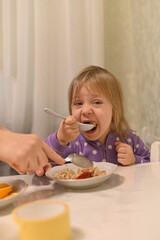 little girl eats with great appetite. a big spoon in her hands
