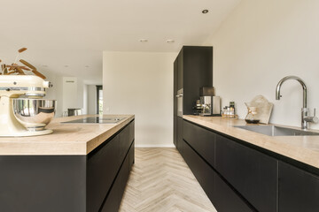 a modern kitchen with wood flooring and black cabinets in the center of the room is a large white mixer on the countertop