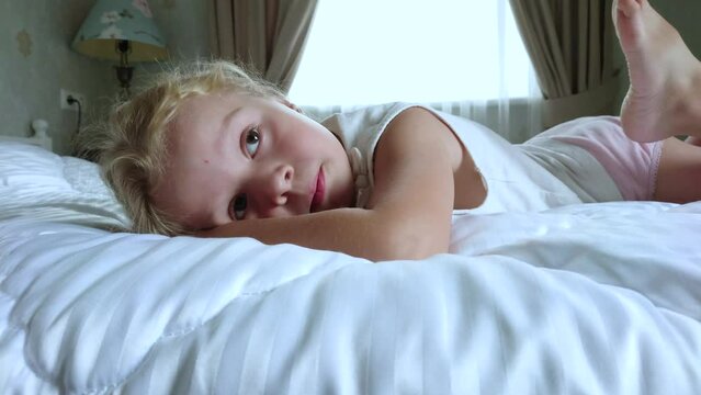 Little cute girl lying in the bed. Concept of awakening in the morning