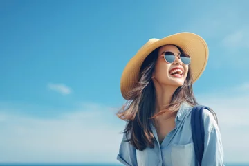 Tuinposter Happy young Asian tourist woman wearing beach hat, sunglasses and backpacks going to travel on holidays on blue background. © Oulaphone