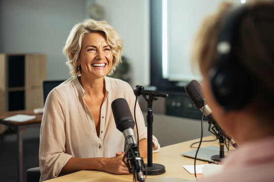 Successful businesswoman or famous politician giving interview and sharing opinion with presenter in studio. Blonde middle-aged lady with microphone answers questions in talk show or podcast.
