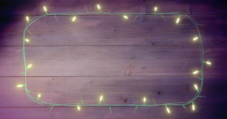 Animation of flickering fairy lights with copy space on wooden background