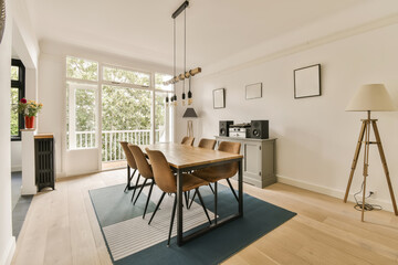 a dining room with wooden flooring and white walls, an area rug is on the right side of the room