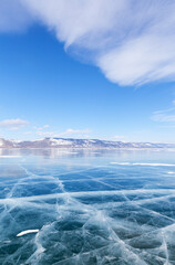 Sunny winter day on frozen Baikal Lake. Small Sea is covered with beautiful clear blue ice with...