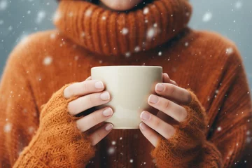 Tuinposter Woman in a warm sweater holding a mug winter, snowing, cold close ups © castecodesign