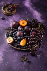 Assortment of purple fruit plum, grape, blueberry and basil