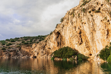 Mineral lake Vouliagmeni is located at the cliff of the mountain.