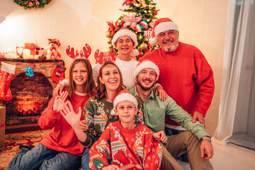Happy parents and their kids having fun near tree indoors. Merry Christmas and Happy Holidays, Grandma, grandpa, mum and child exchanging gifts. Loving family with presents in room.
