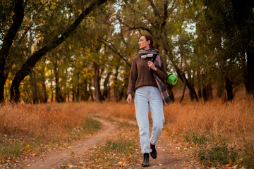 Fototapeta premium woman walking in the forest, female traveler walking through the forest on a sunny autumn day, young Caucasian woman hiking, girl with a tourist backpack walking in the forest