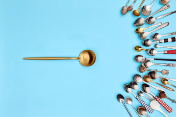 Tips of cutlery. Top view photo one soup-spoon surrounded of variety of antique silverware and gold...