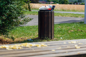 Public trash can in a park filled with overflowing trash