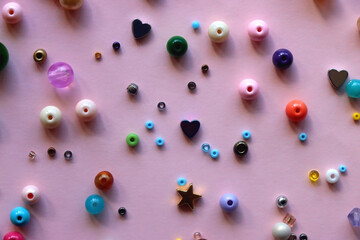 Various colorful beads on bright pink background. Top view.