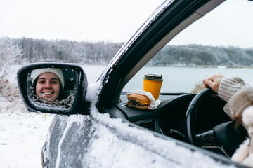 woman in car eating burger and drink coffee