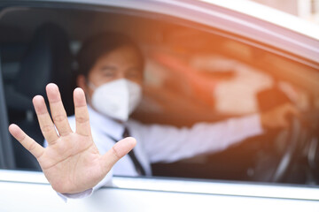 Businessman drives a car wearing a mask to protect against COVID-19 germs