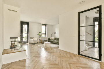 a living room with wood flooring and white walls, there is an open door leading to the dining area - obrazy, fototapety, plakaty