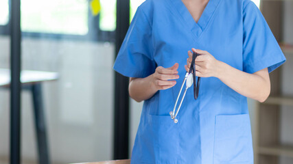 Female doctor in uniform holding a stethoscope waiting to examine a patient. A female doctor holds...