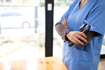 Female doctor in uniform holding a stethoscope waiting to examine a patient. A female doctor holds a stethoscope to prepare for treating patients in the hospital. Copy Space for inserting medical text
