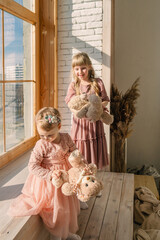 two cute little sisters with bear toys playing near window