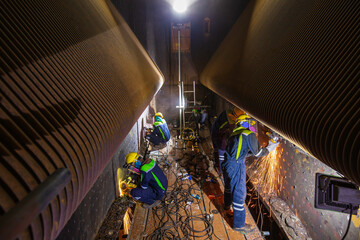 Male worker  grinding and welding furnace tube on steel plate in to confined